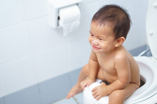 An Asian baby sit on a toilet