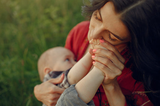 Woman sitting on a blanket and breastfeeding her little son
